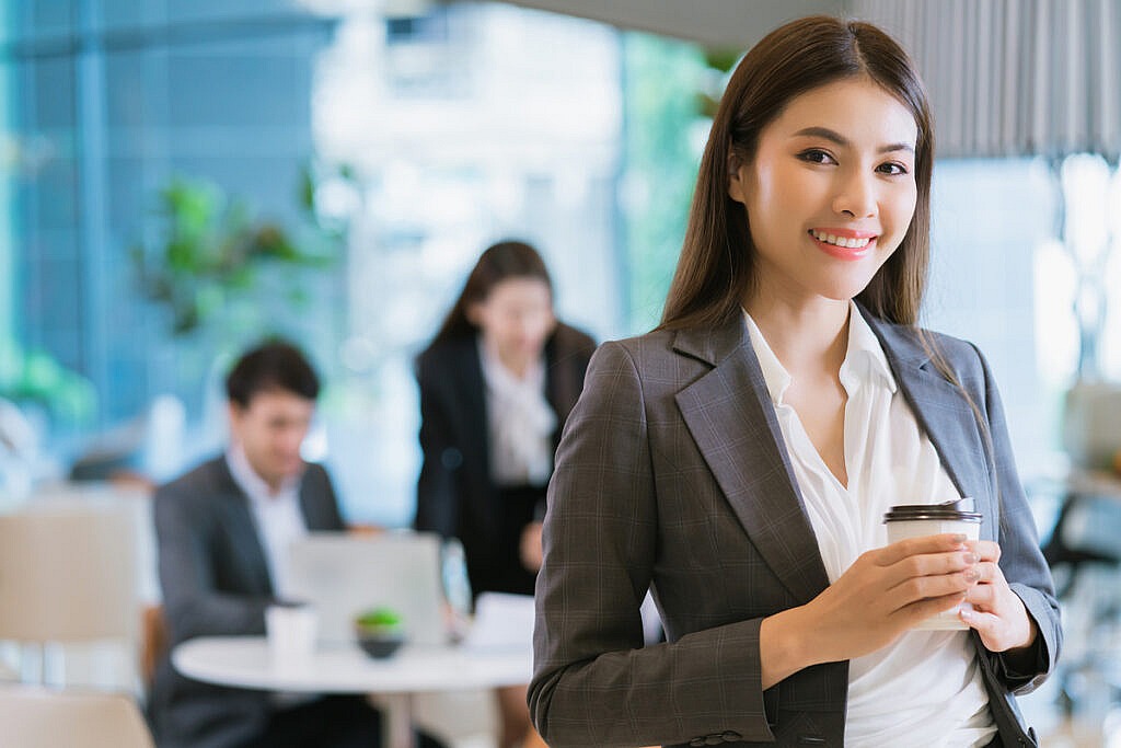 close up smart attractive asian business female smile hand hold hot drink with modern office background 1